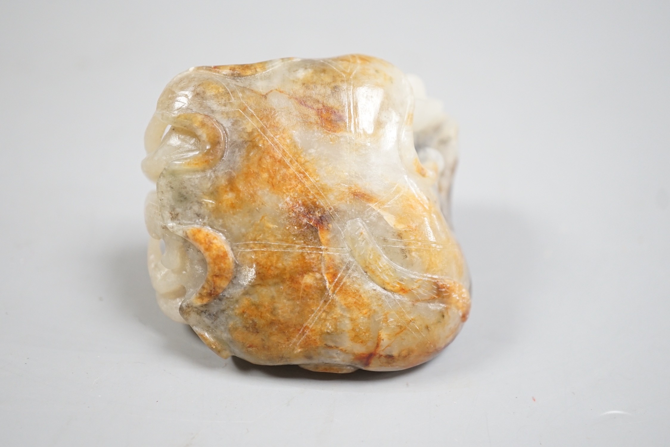 A Chinese pale grey and russet jade carving of carp amid lotus, 7.3 cm